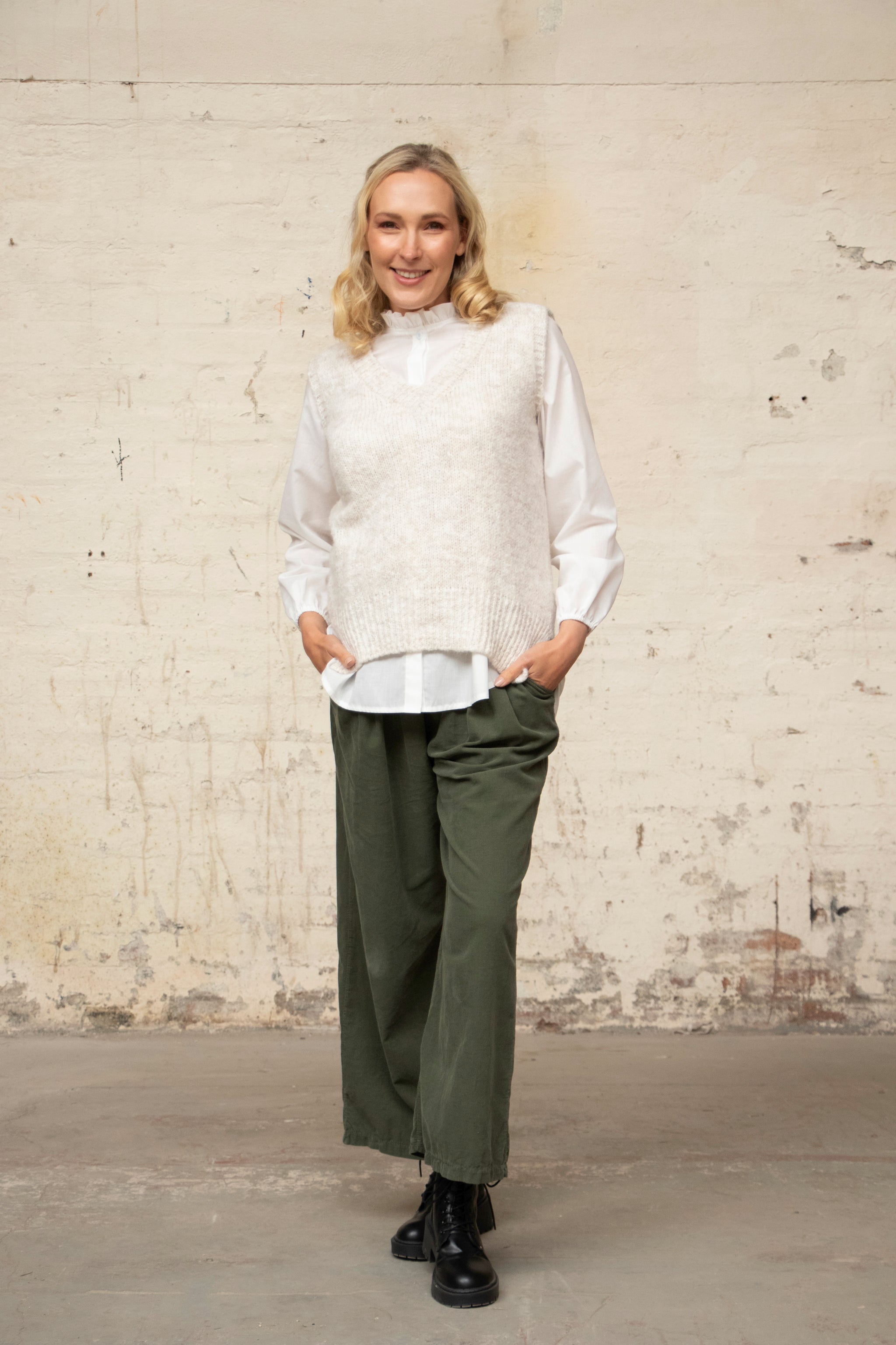 model wearing a cream sleeveless knitted tank top with a v neck and ribbed texture