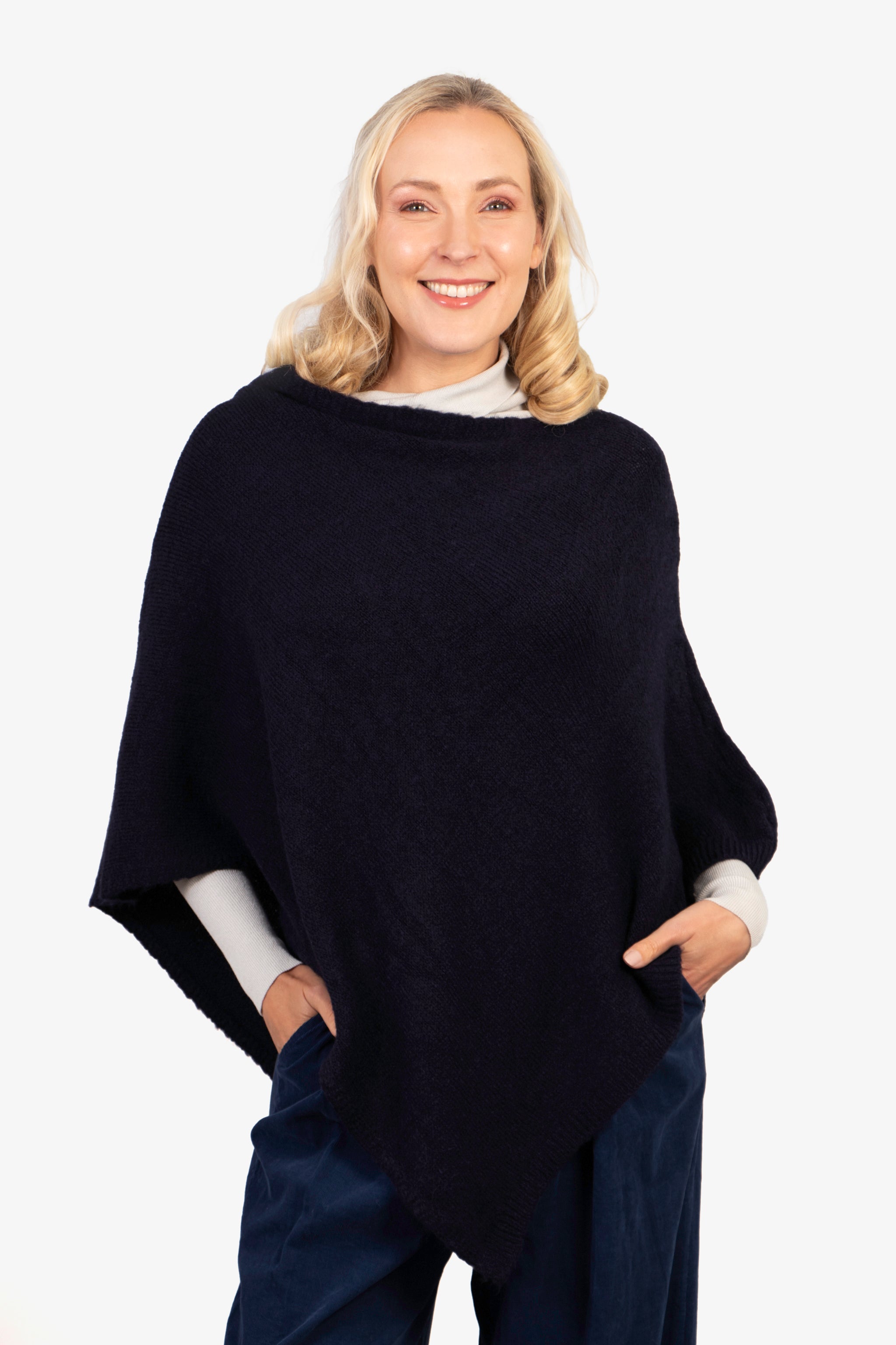 model wearing a navy blue knitted asymmetrical poncho with a cowl neck