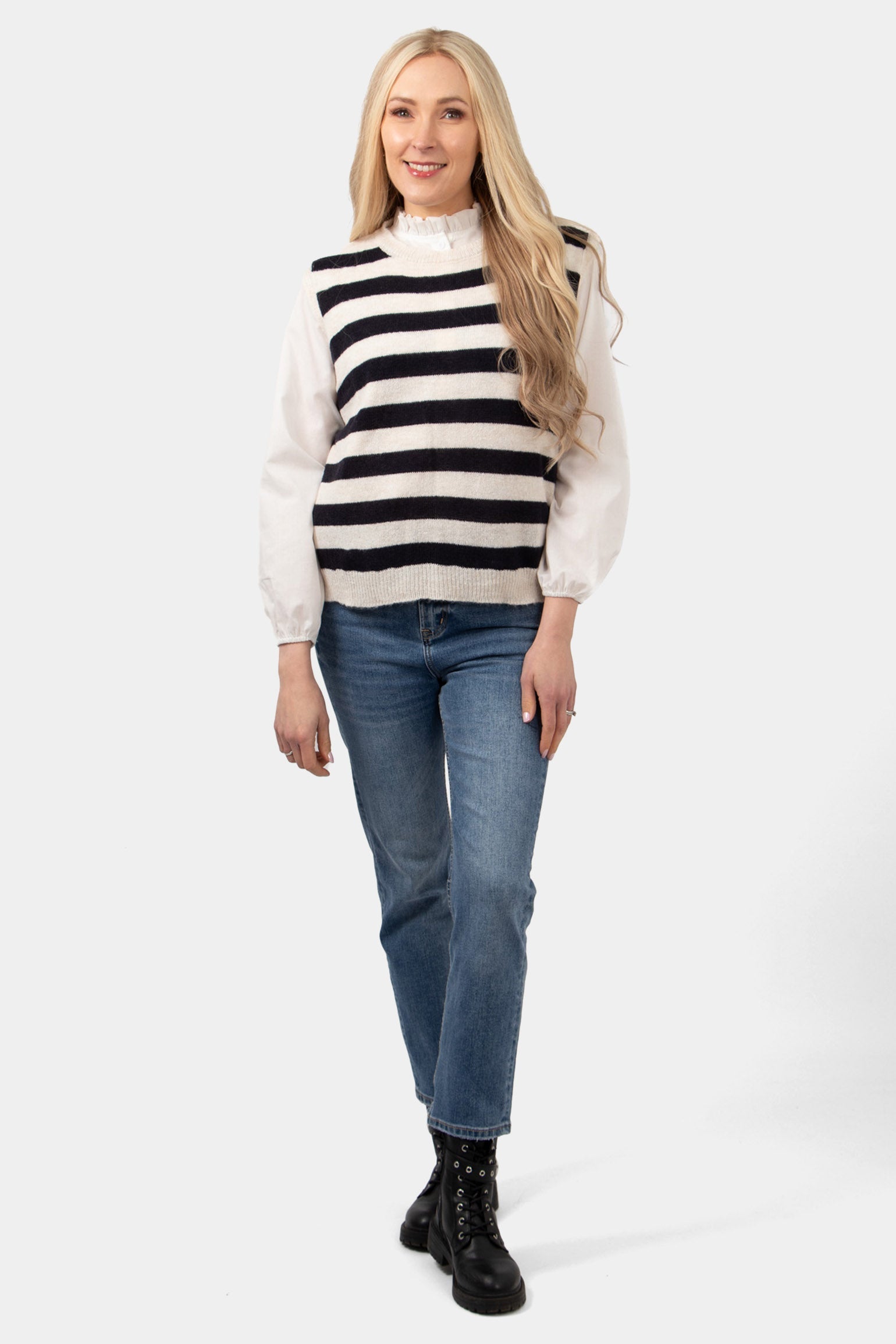 cream and navy blue knitted striped tank top worn by a model and styled over a white cotton blouse and paired with casual blue jeans and black biker boots.