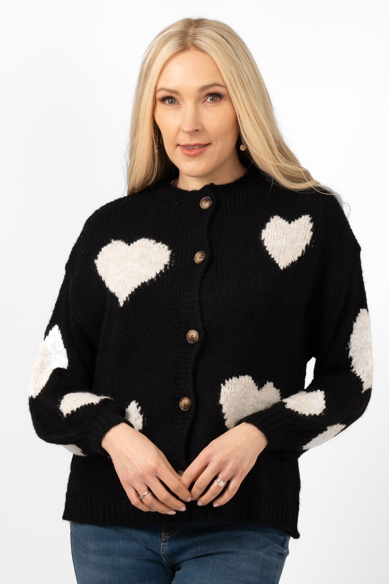 model wearing a black button up cardigan with a pattern of large cream love hearts all over the design.