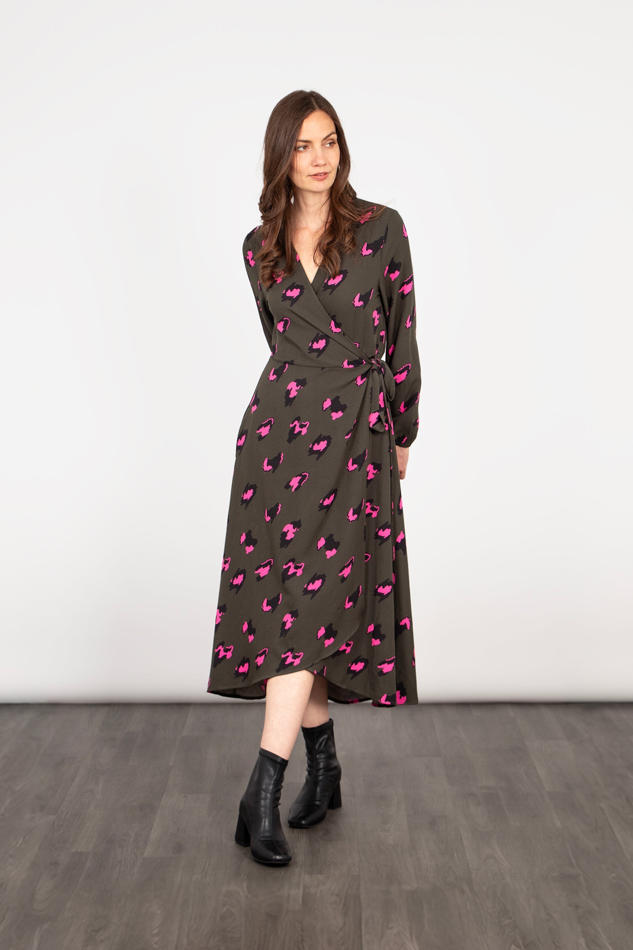 model wearing a khaki and pink leopard print midi wrap dress, the dress has long sleeves and a v-neck