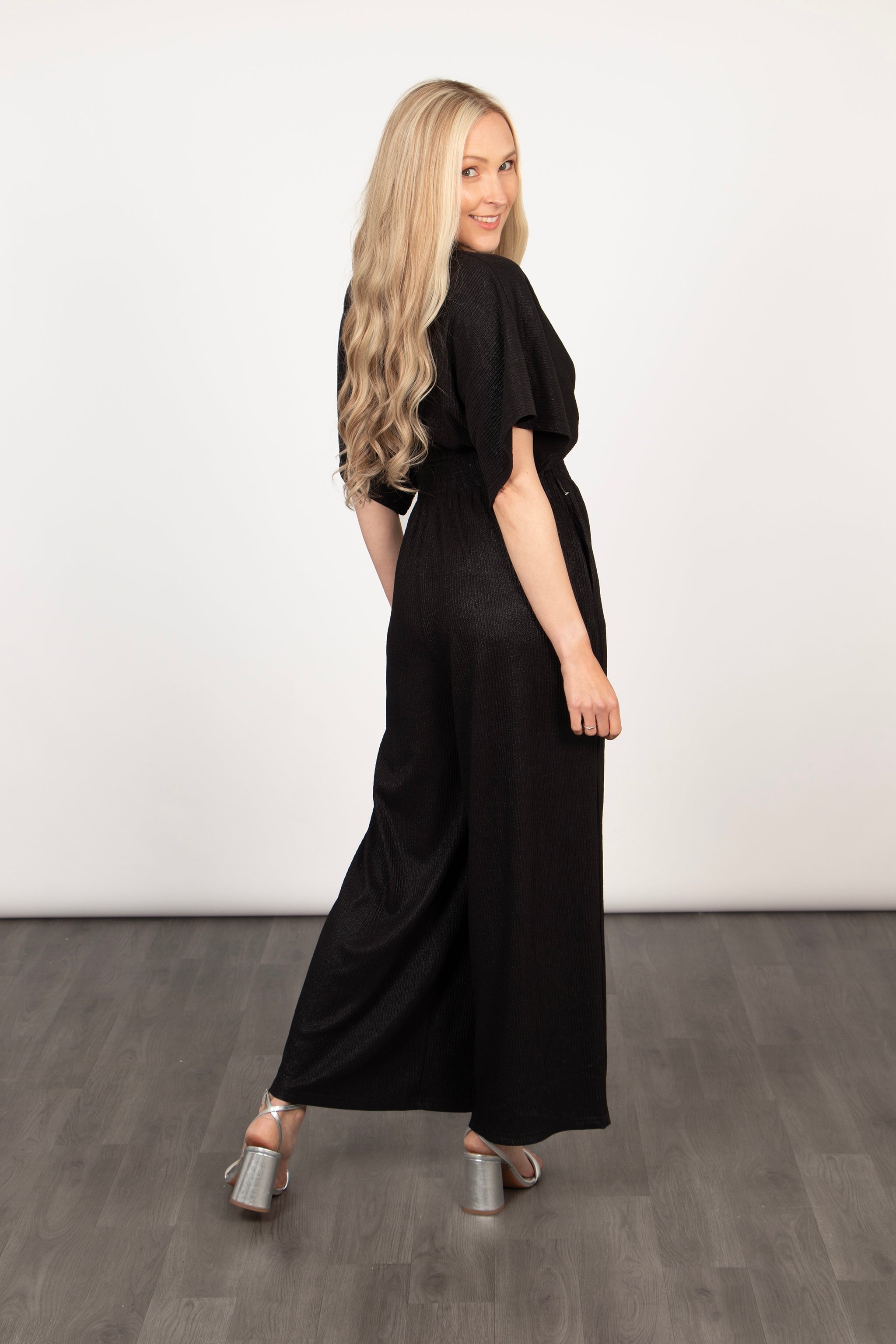 model showing the back of the jumpsuit, showing the wide leg feature and short angel sleeves