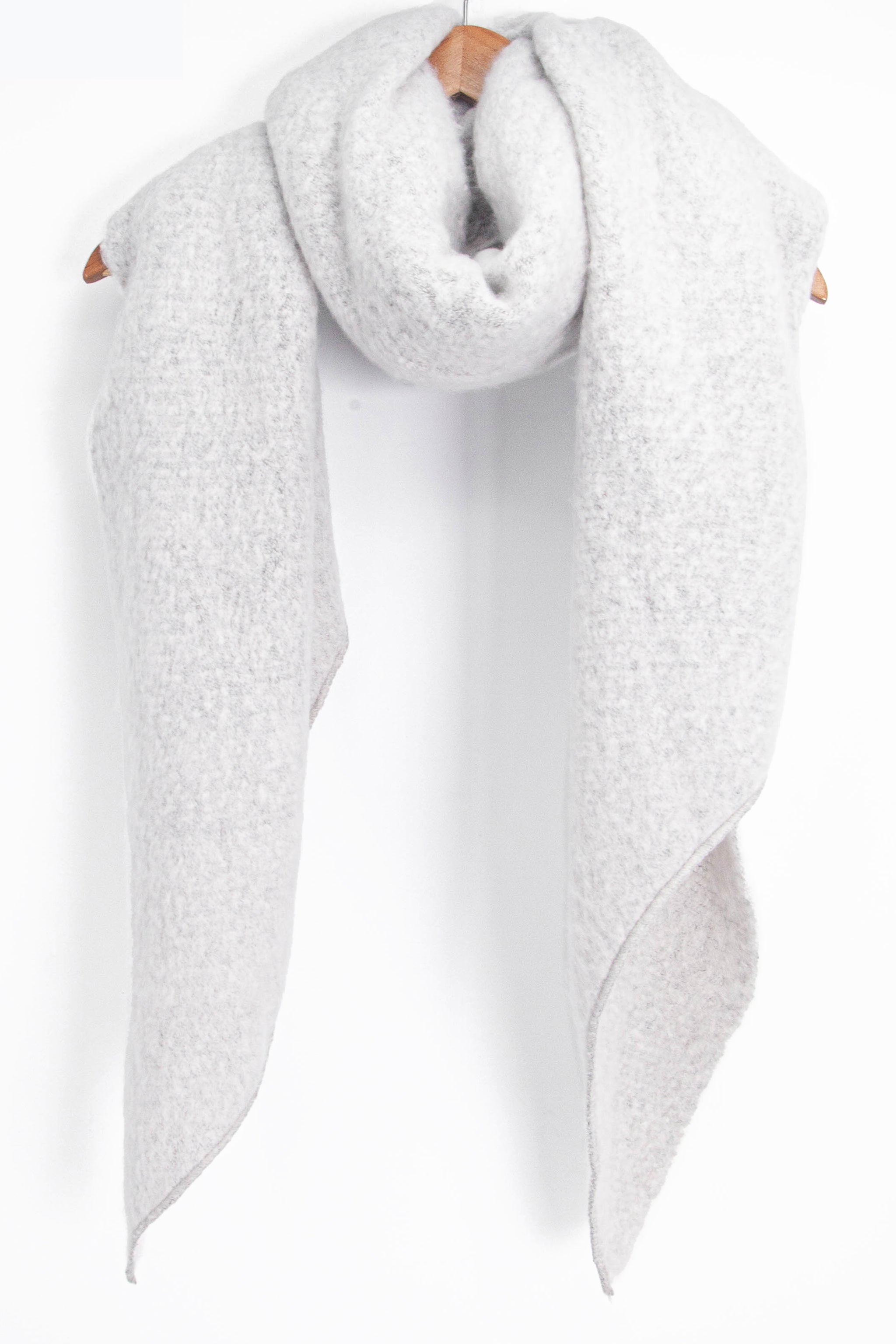 asymmetric light grey winter scarf draped around a coat hanger