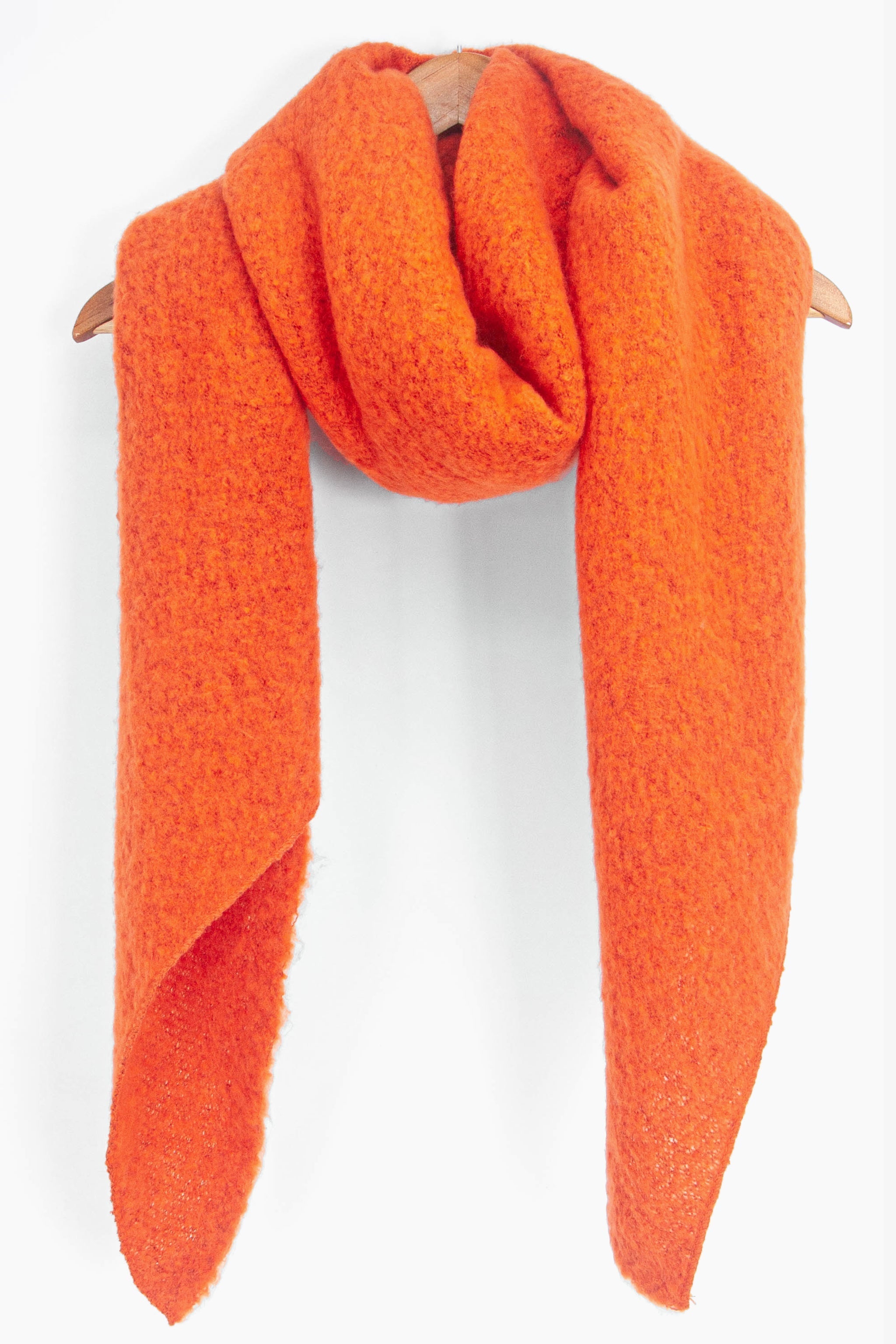 asymmetric orange winter scarf draped around a coat hanger