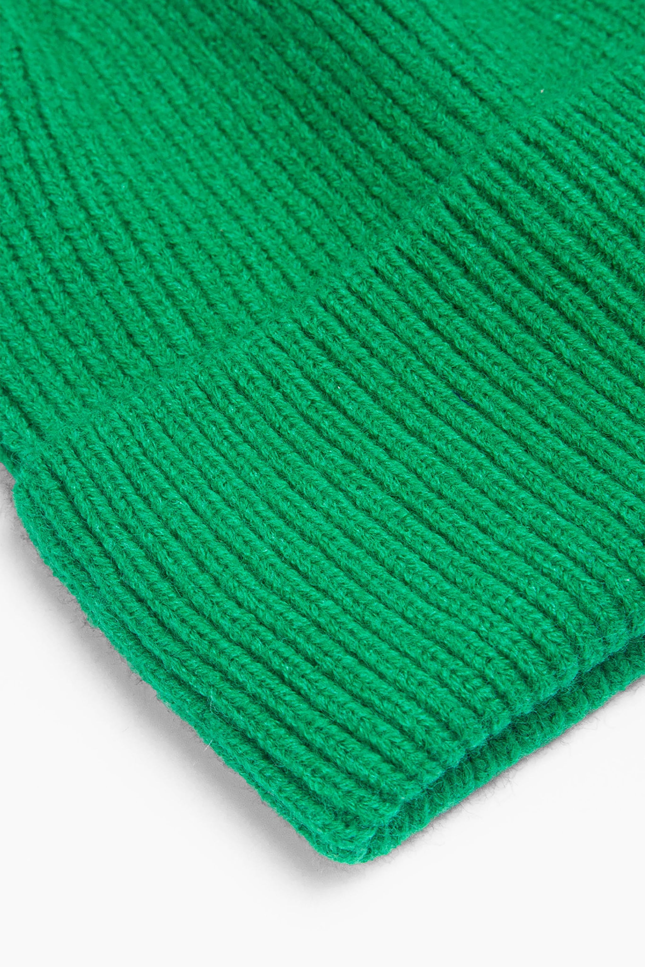 close up of the brim of the green knitted beanie hat, showing the ribbed design