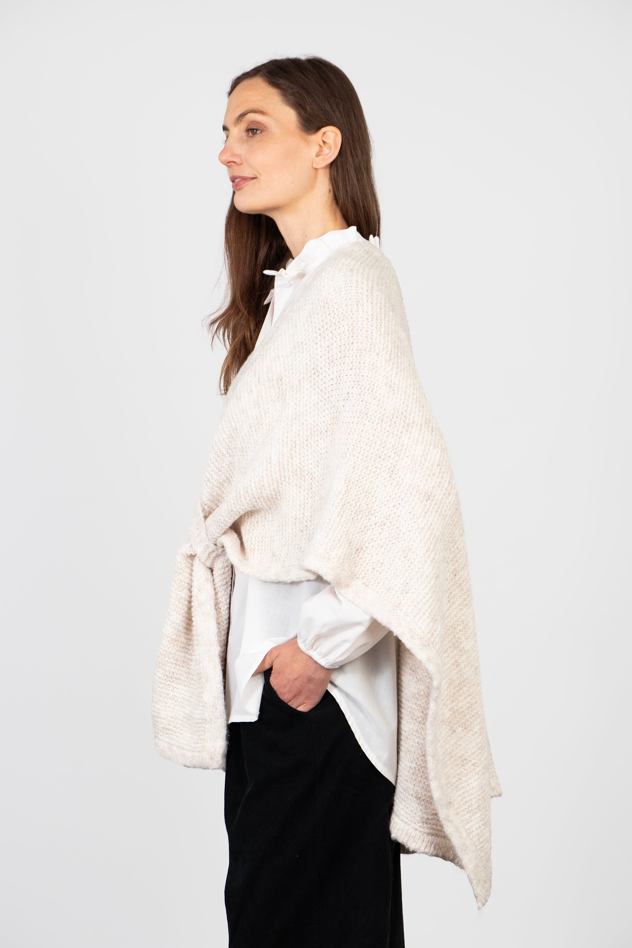 side view of the cream tuck wrap, showing how it fastens and the asymmetric hemline