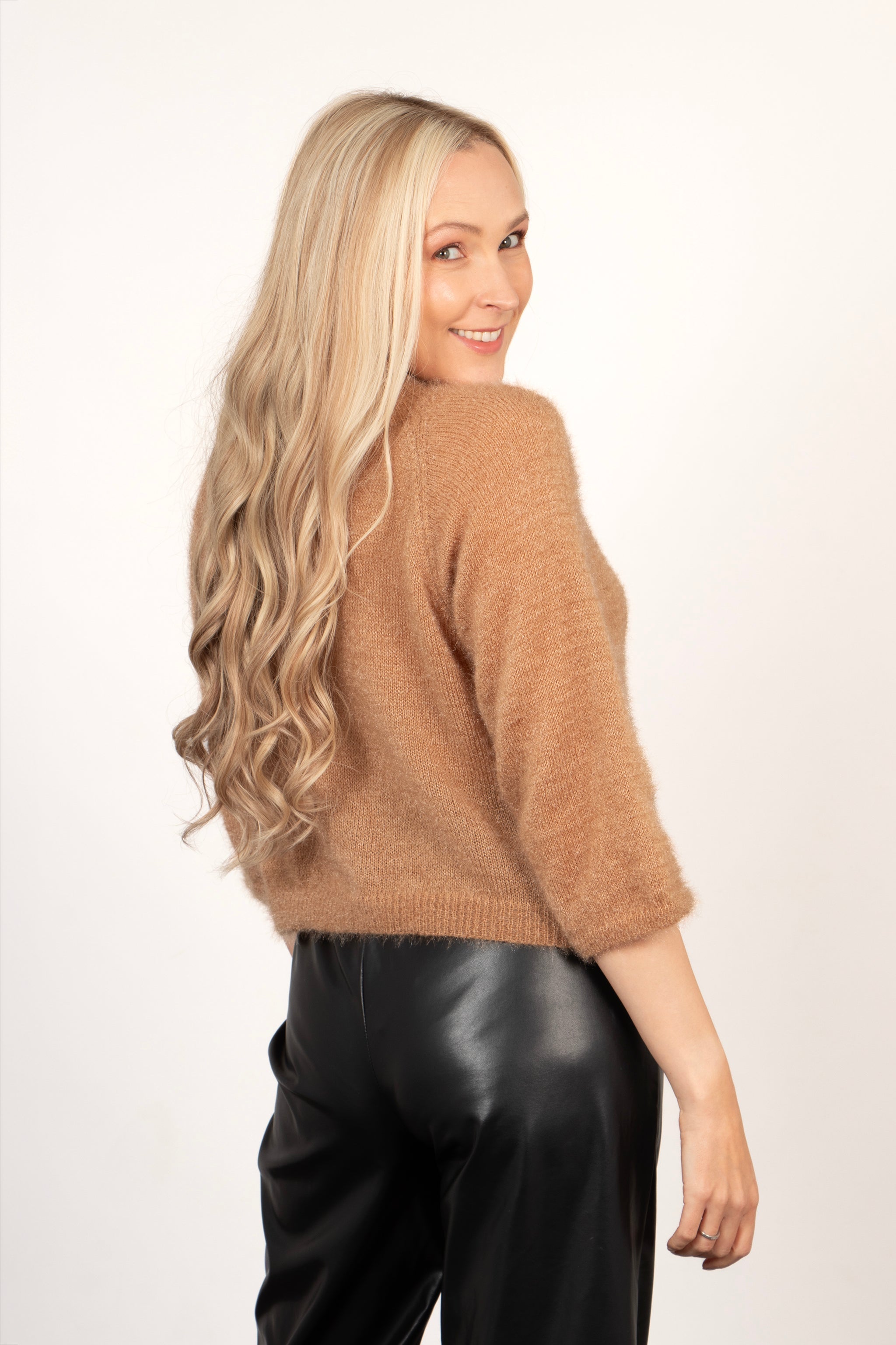 model showing the back of the jumper, showing the cropped length of the piece and the 3/4 cropped sleeves