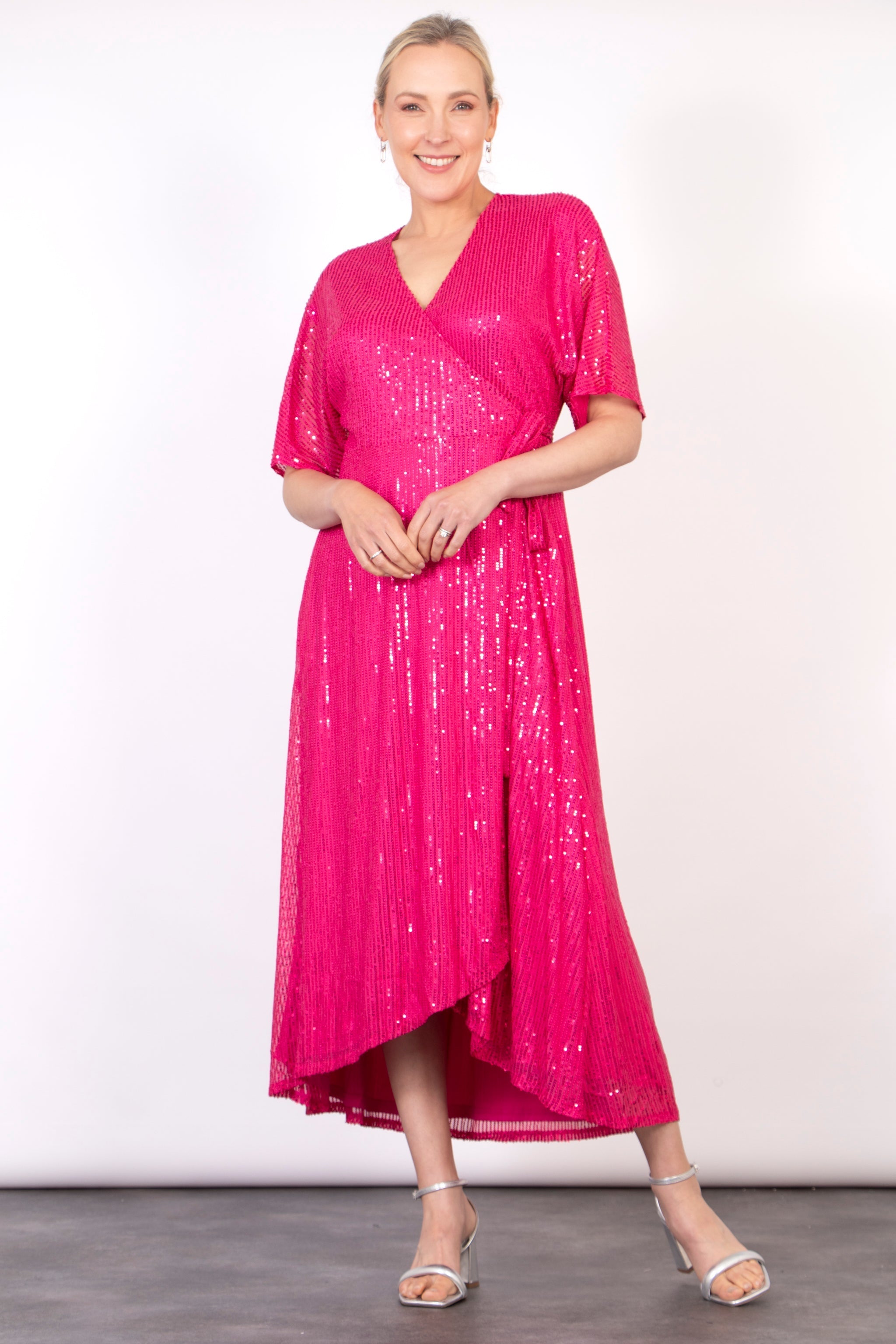model wearing a pink sequin wrap dress with waist tie and v-neck 
