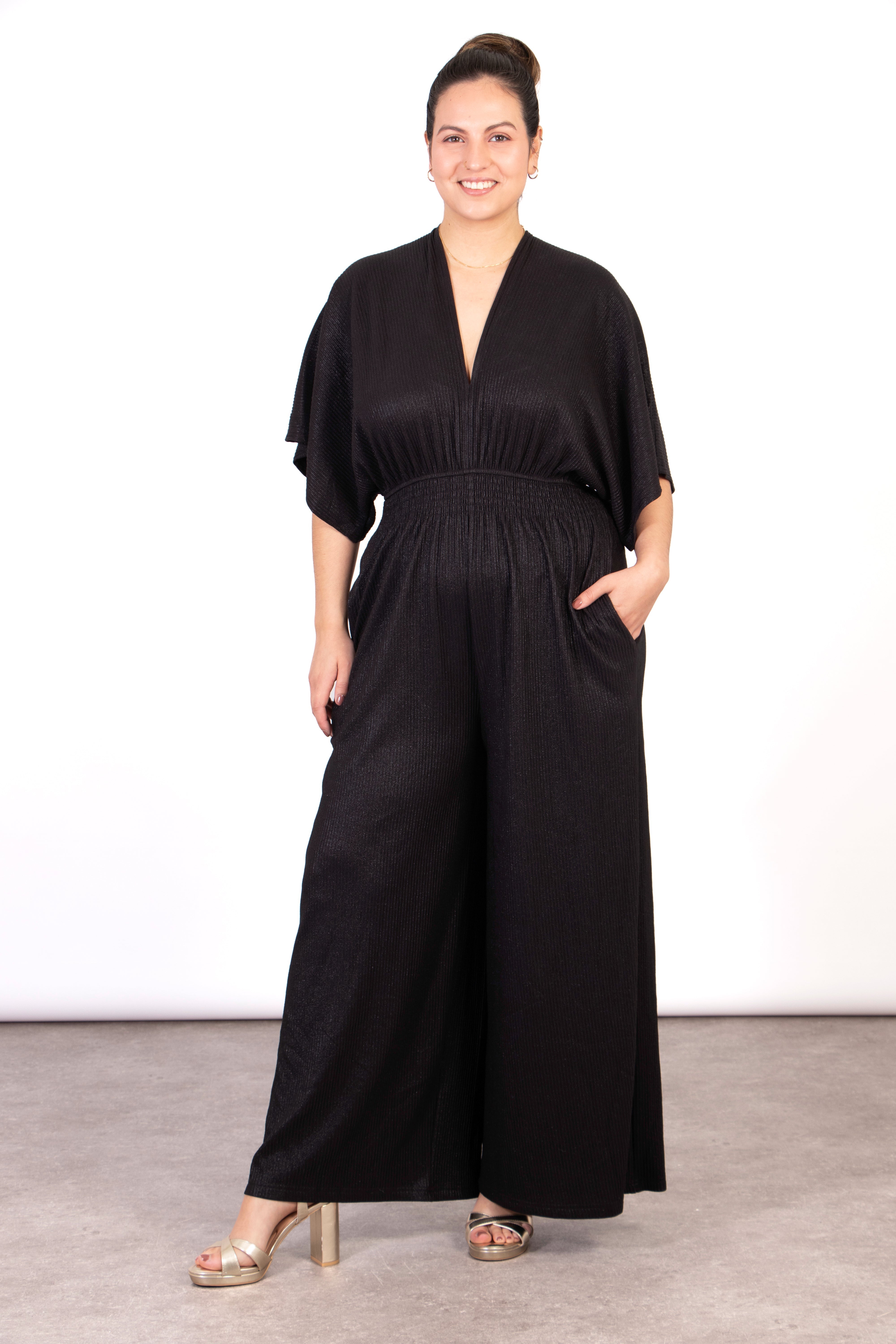 model wearing a shimmery metallic black wide leg jumpsuit, with short angel sleeves and a v-neck
