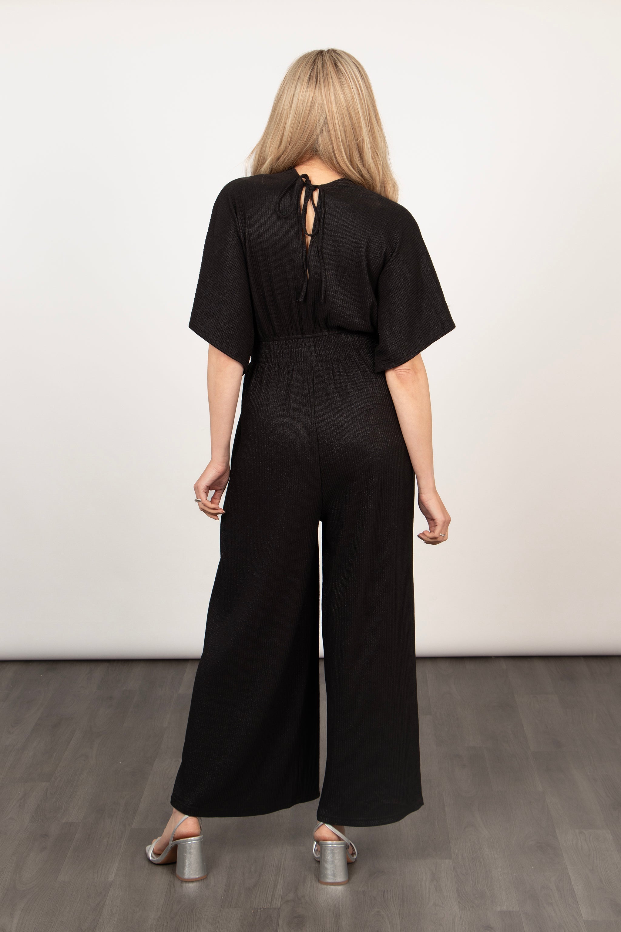 model showing the back of the jumpsuit highlighting the tie at the back of the neck